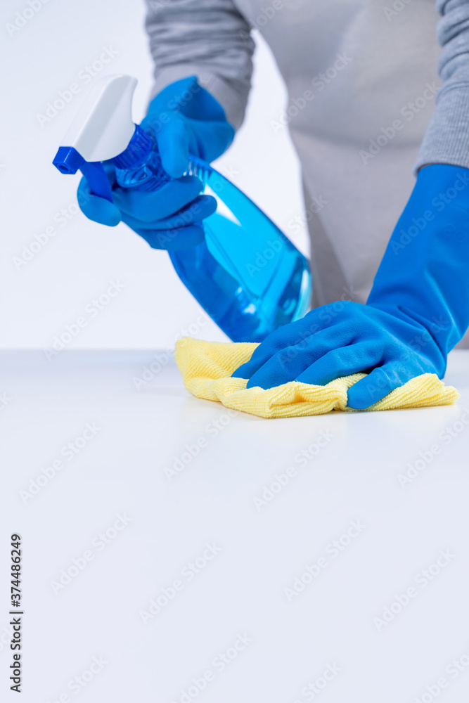 穿着围裙的年轻女管家正在打扫卫生，用蓝色手套擦拭桌子表面，湿黄色