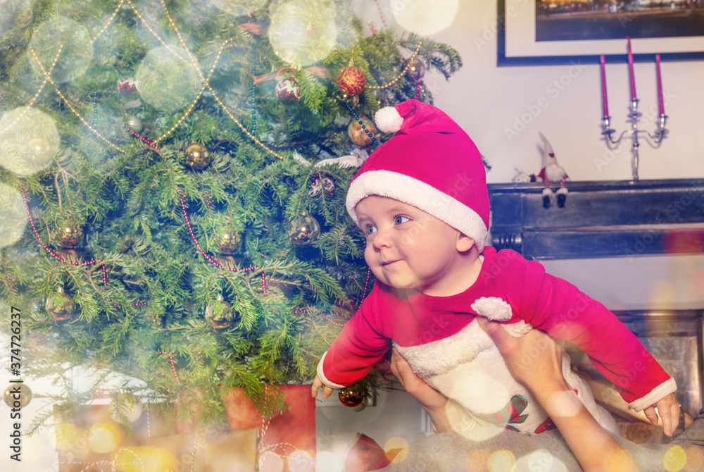 妈妈手中的快乐小男孩在圣诞树前玩耍