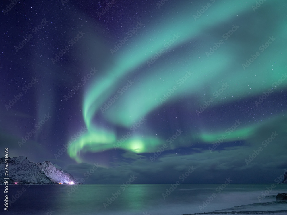 北极光，挪威森加群岛。星星、移动的云层和北极光。山脉和海洋