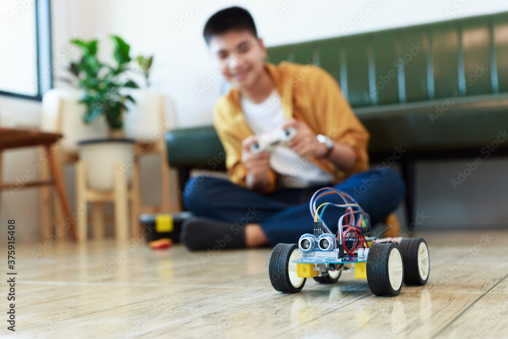 年轻的亚洲青少年将能量和信号电缆插入玩具车车间的传感器芯片。