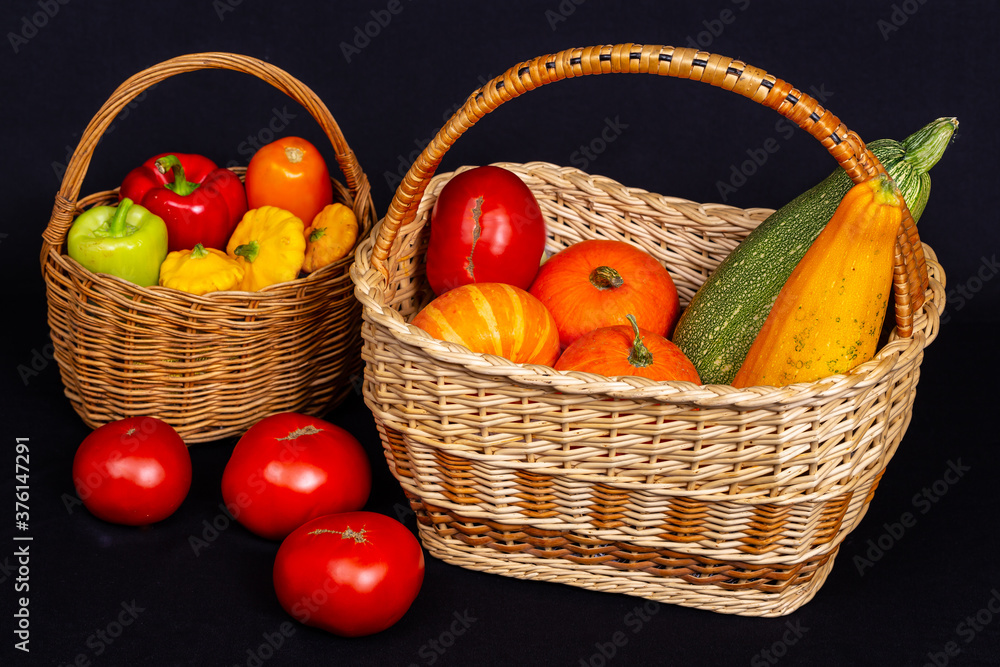 黑色背景柳条篮中五颜六色的有机蔬菜。南瓜、番茄、南瓜、西葫芦。