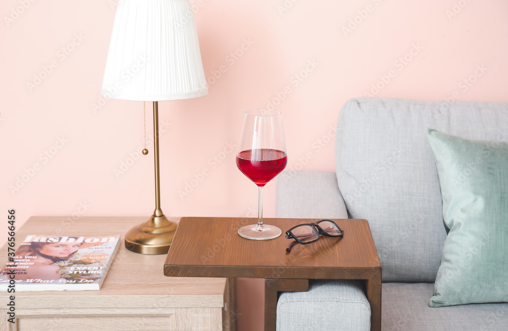 房间扶手桌上的一杯带眼镜的葡萄酒