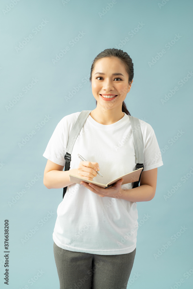 一个快乐友好的女学生的肖像，背包里装着蓝色背景下的书