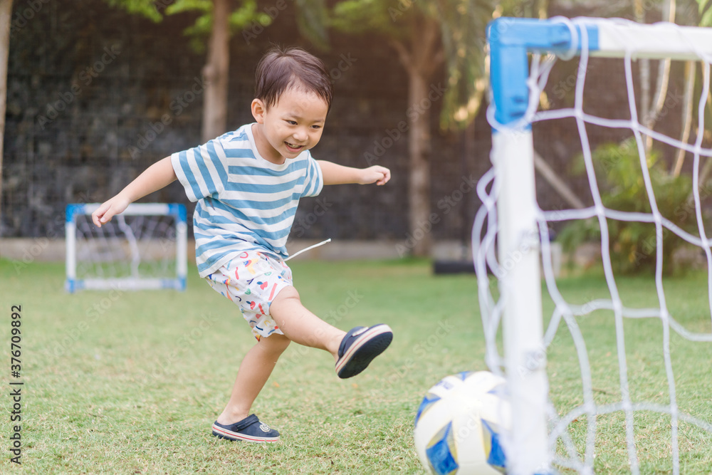 亚洲蹒跚学步的男孩在户外足球场公园踢足球。3岁亚洲男孩ki