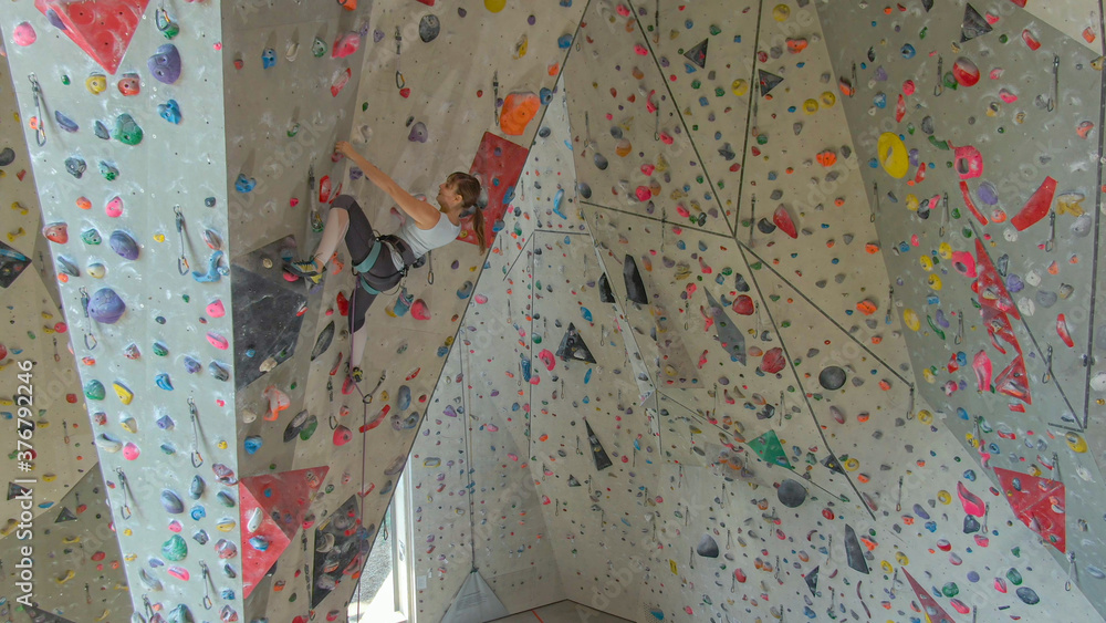 无人机：年轻的女攀岩者在凉爽的室内训练中心攀岩。