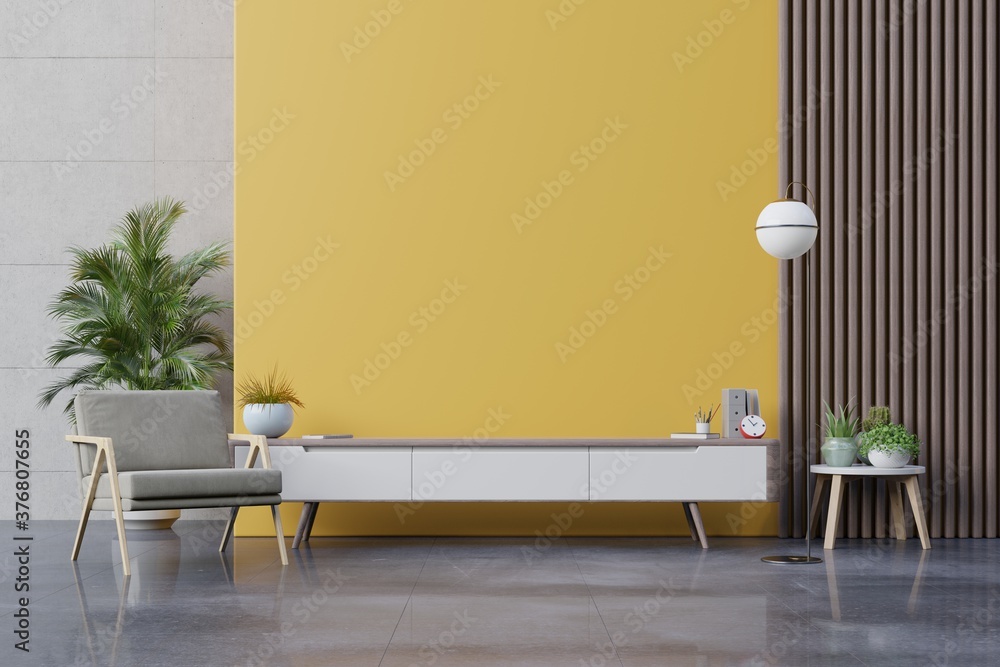 现代客厅的橱柜电视，黄色墙壁背景上有扶手椅、灯、桌子、花草