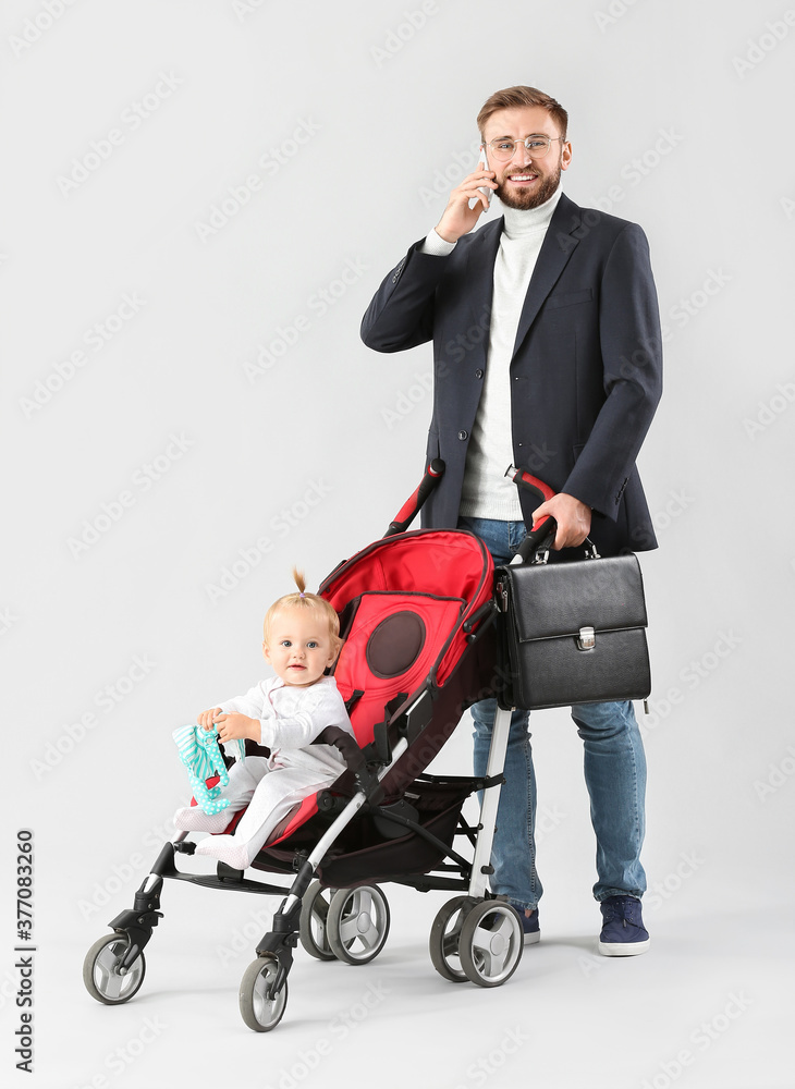 父亲和他可爱的婴儿在婴儿车里，背景为浅色