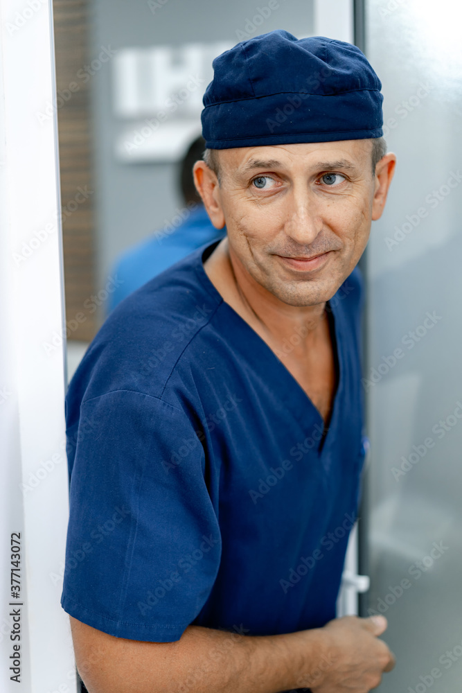 微笑的医生在房间里行走时看着侧面。手术室入口附近的男医生
