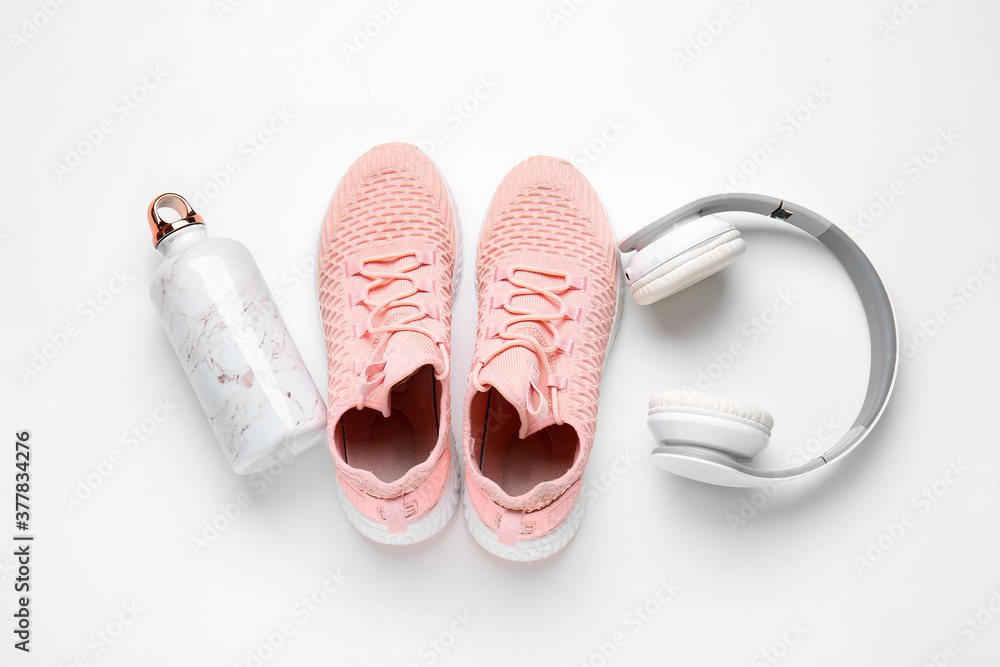 白色背景的运动鞋、水瓶和耳机