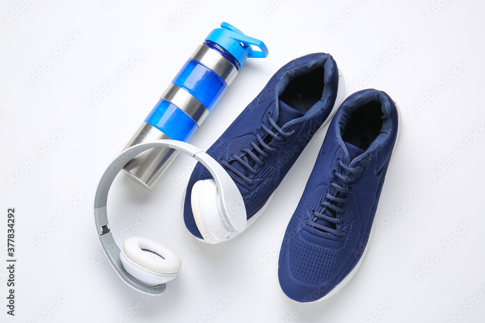 白色背景的运动鞋、水瓶和耳机
