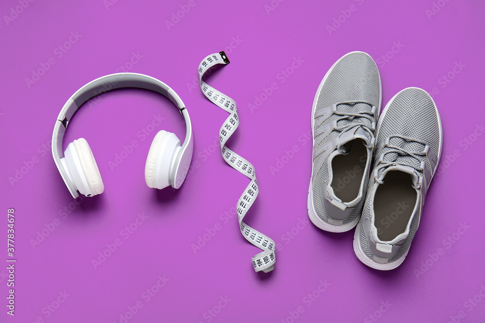 彩色背景的运动鞋、卷尺和耳机。减肥概念