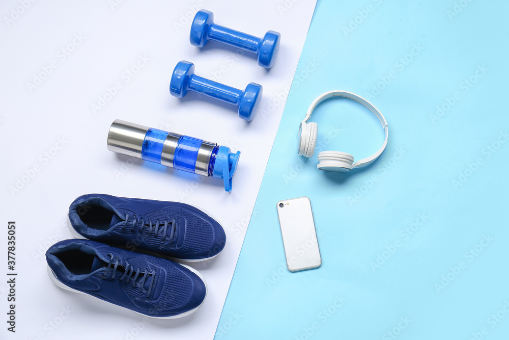 彩色背景的运动鞋、水瓶、哑铃、手机和耳机