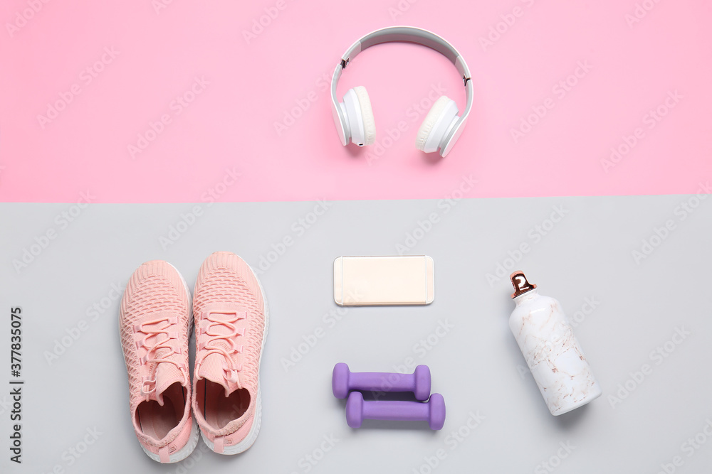 彩色背景的运动鞋、哑铃、水瓶、手机和耳机