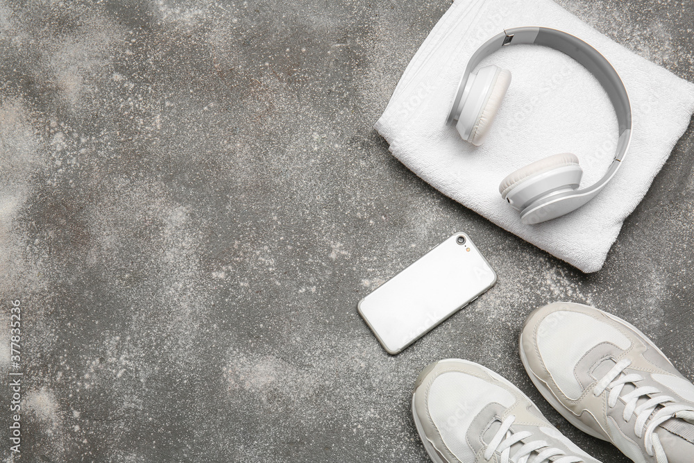 灰色背景的运动鞋、毛巾、手机和耳机