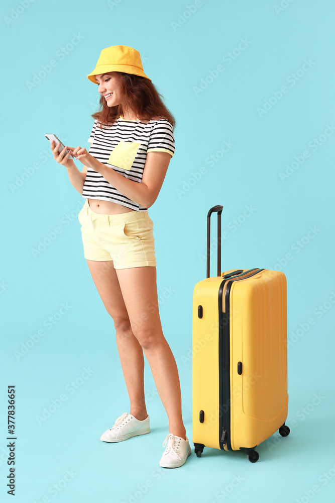 彩色背景带行李和手机的女游客