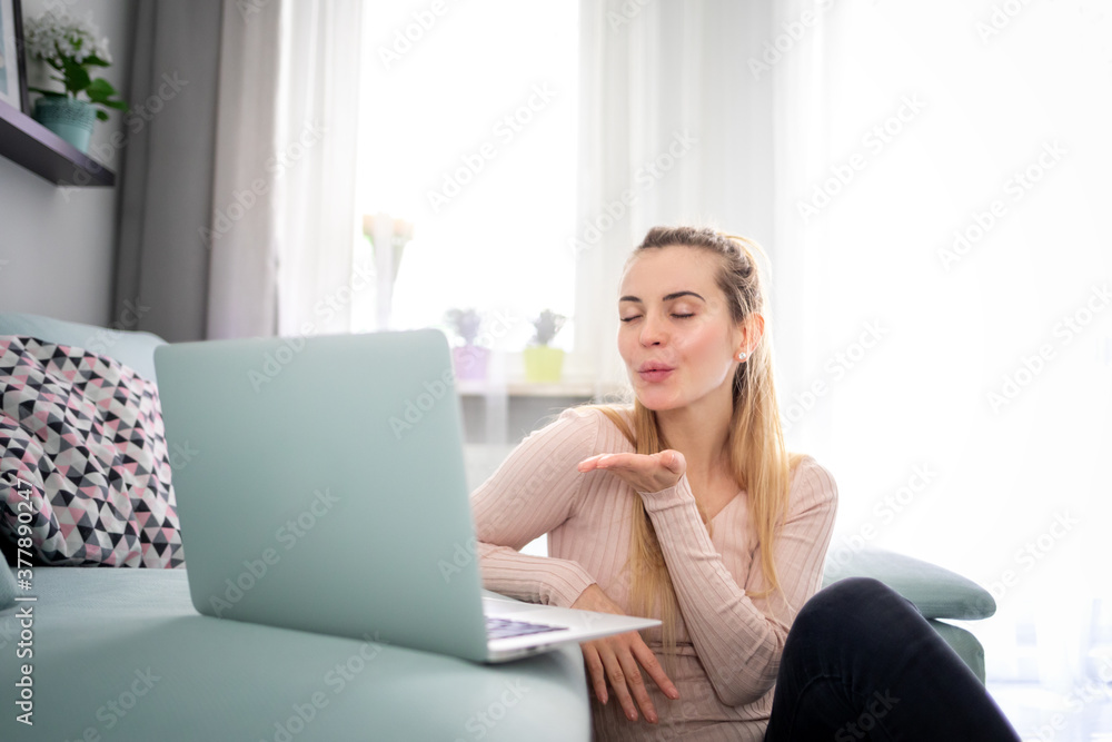 快乐的年轻女人坐在家里用笔记本电脑视频聊天