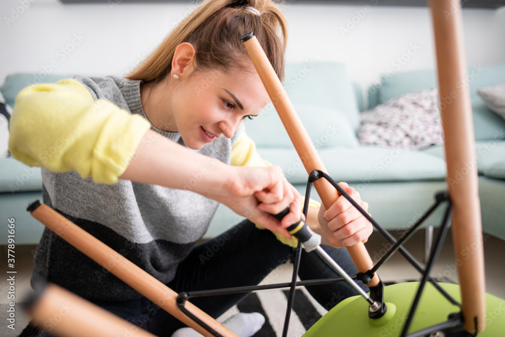 专注女性在家用螺丝刀修理椅子DIY概念