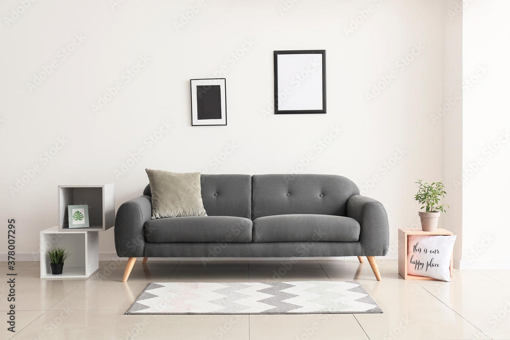 Comfortable sofa near white wall in room