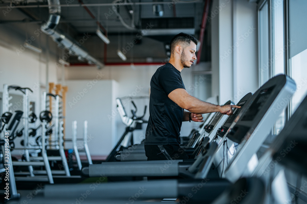Man running in machine treadmill at fitness gym.