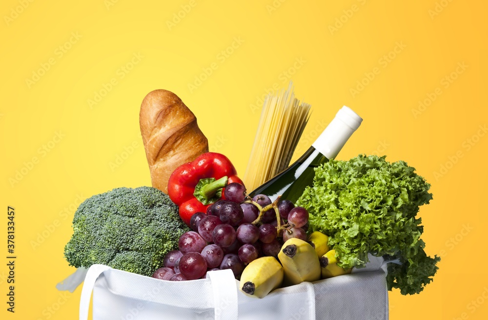 Full shopping bag with vegetable on colored background