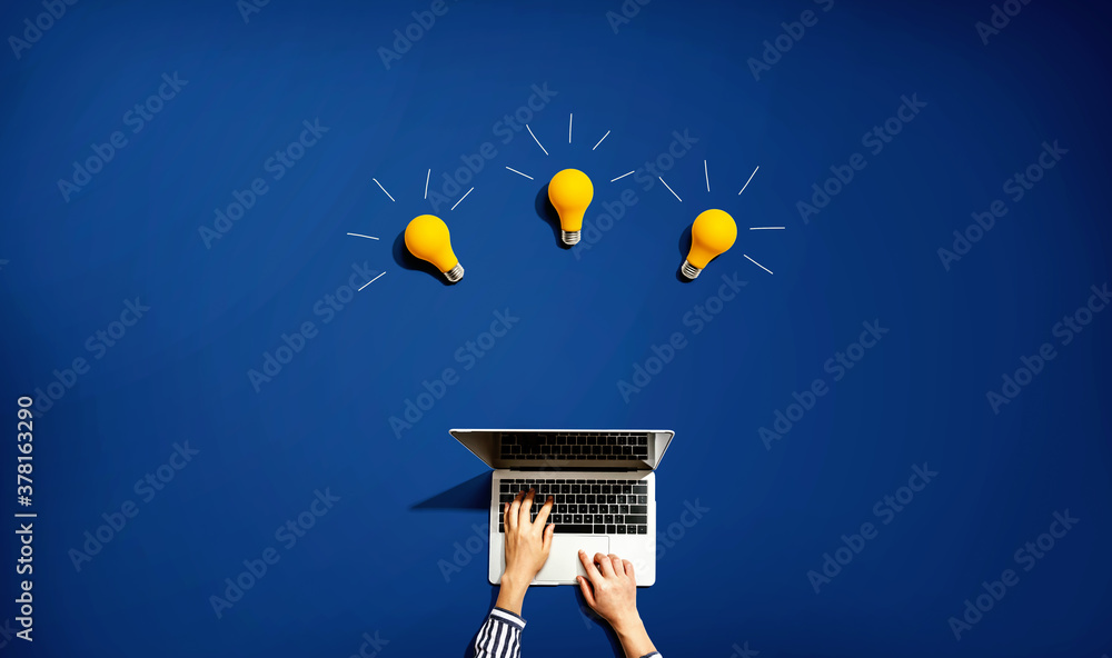 Person using a laptop computer with three light bulbs from above
