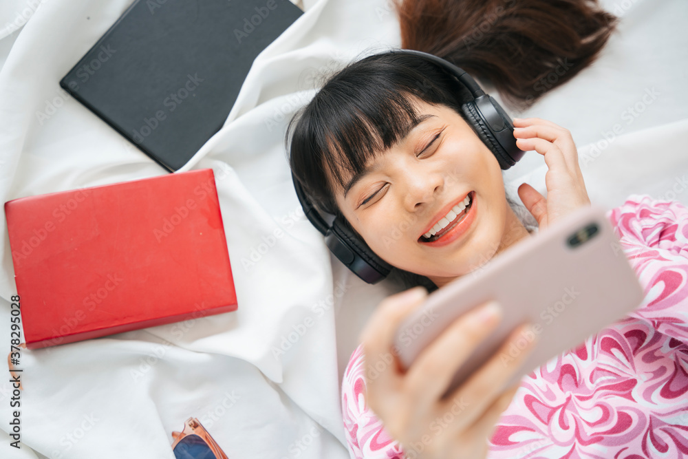 Young asian woman in pink shirt enjoy listen to music with headphone and smartphone.