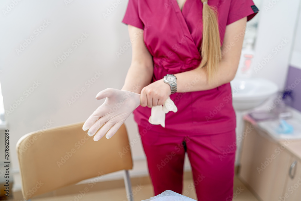 Woman doctor wearing medical sterille gloves. Selective focus on hands. Modern clinic interior in th