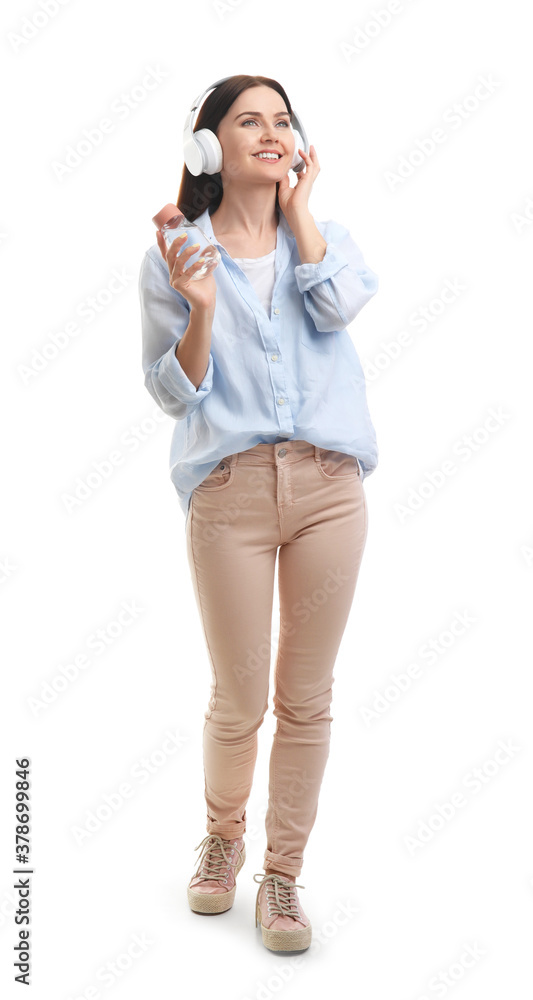 年轻女子拿着一瓶水在白色背景下听音乐