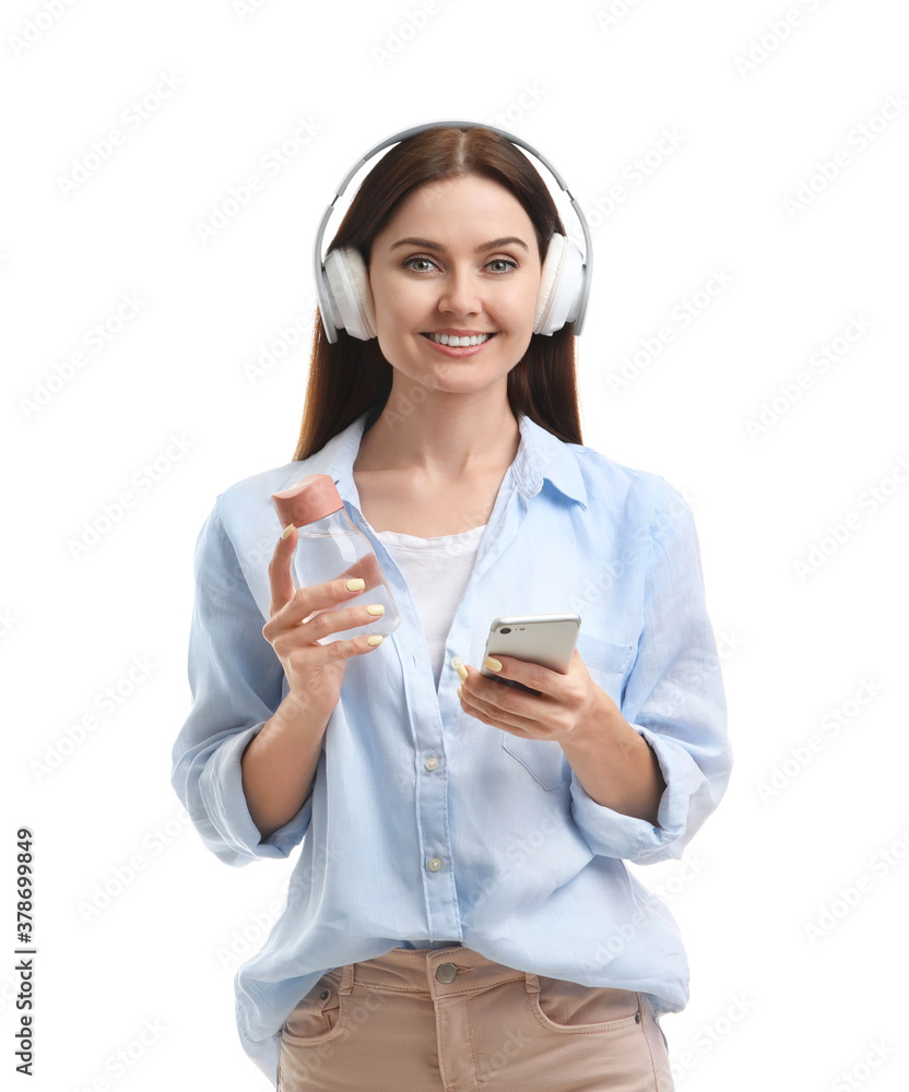 Young woman with bottle of water listening to music on white background