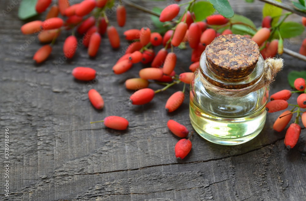 Barberry essential oil in a glass bottle on old wooden table for aromatherapy,skin care or spa.Berbe