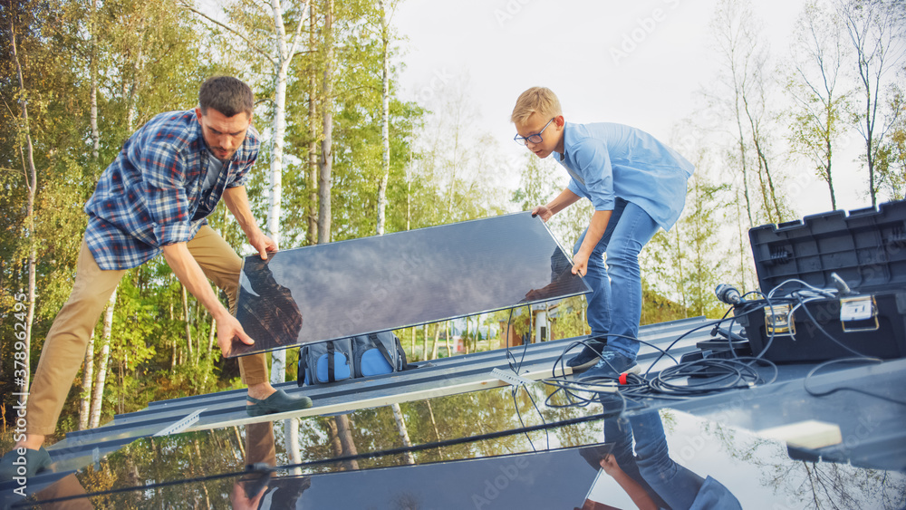 Father and Son Installing Solar Panels to a Metal Basis. They Work on a House Roof on a Sunny Day. C