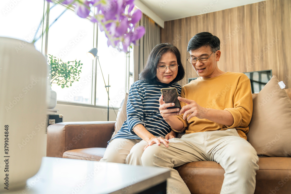 幸福的亚洲老情人夫妇拿着智能手机看着手机屏幕大笑休闲r
