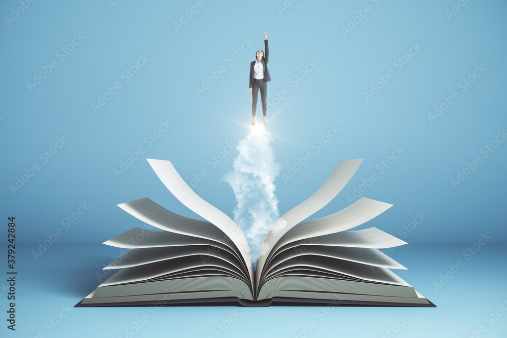 Businesswoman  flies over open book on blue background.
