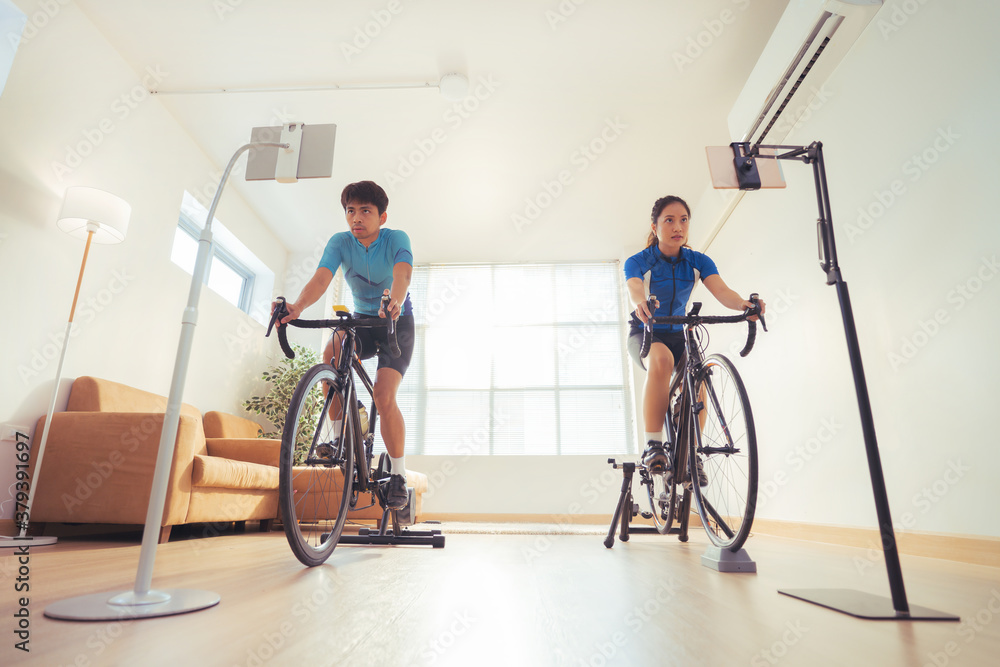 Asian couple. They are exercising in the home.By cycling on the trainer and play online bike games.