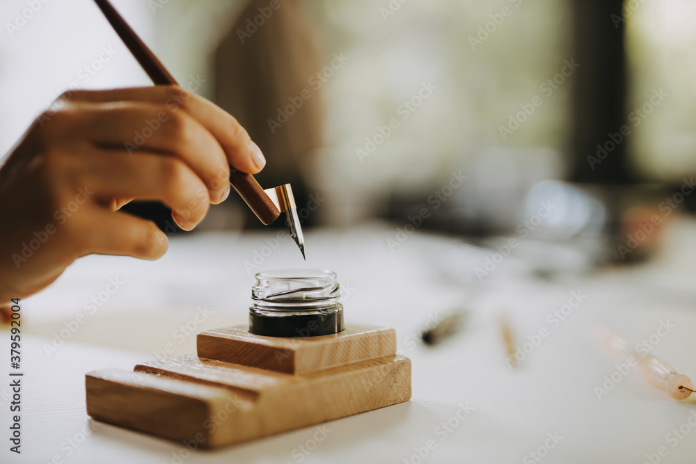 Calligraphy concept. Close-up image of artist holding fountain pen.