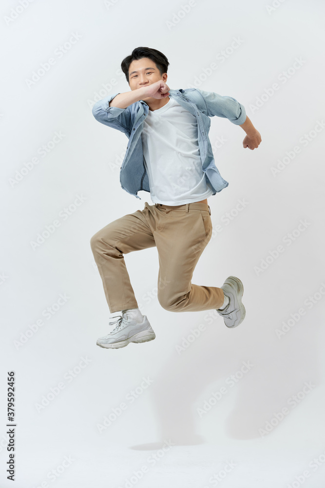 Young Asian man jumping in the air on white background.