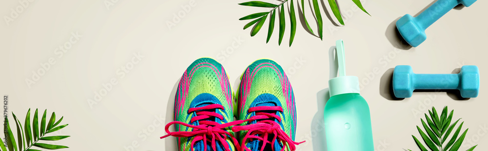 Fitness shoes and dumbbells with tropical plants - flat lay