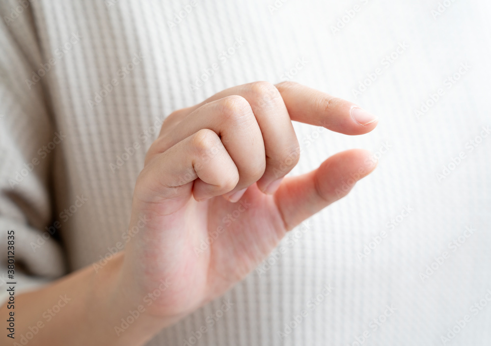 A womans hands in a gesture of plucking in front of her body
