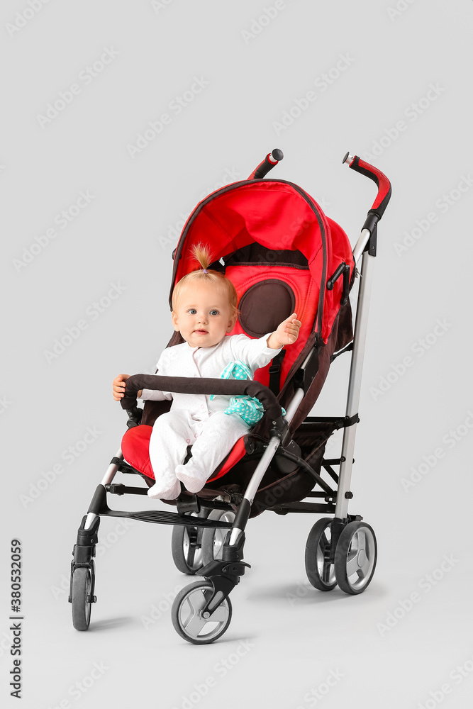Cute little baby in stroller on light background
