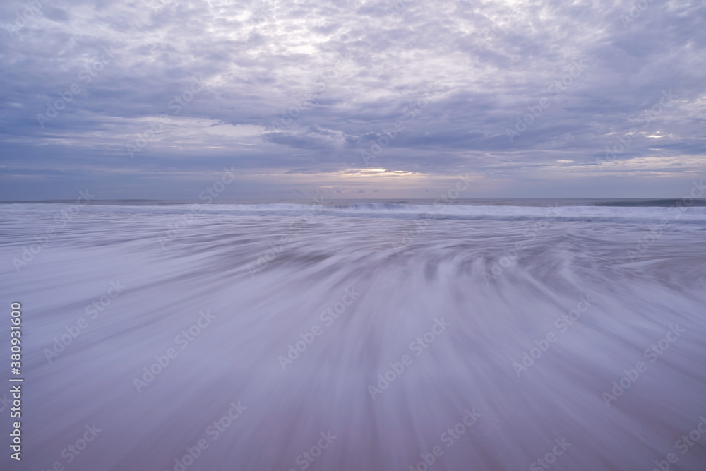 Long speed shutter of tropical sandy beach with sky and clouds over sea.