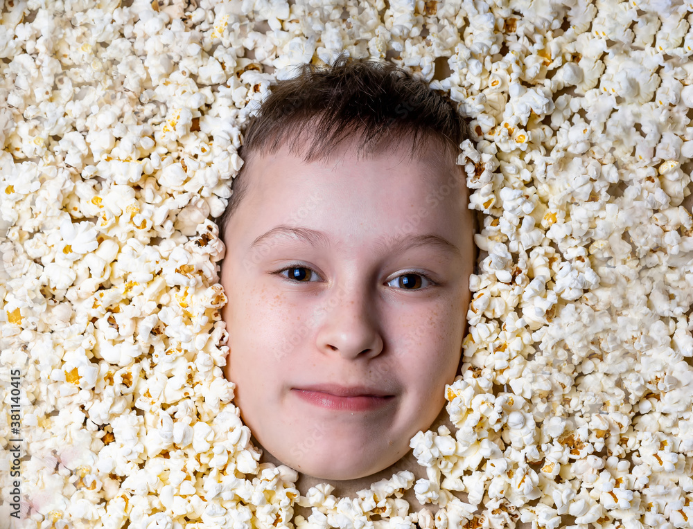 Creative portrait of a boy with face surrounded by popcorn. Art photo.