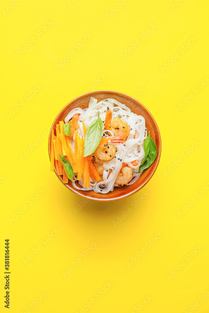 Bowl with tasty rice noodles and shrimps on color background