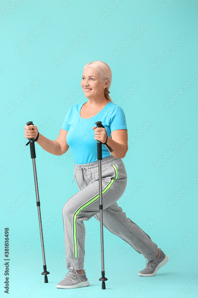 Mature woman with walking poles on color background