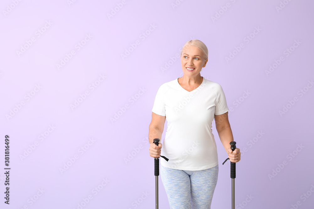 Mature woman with walking poles on color background
