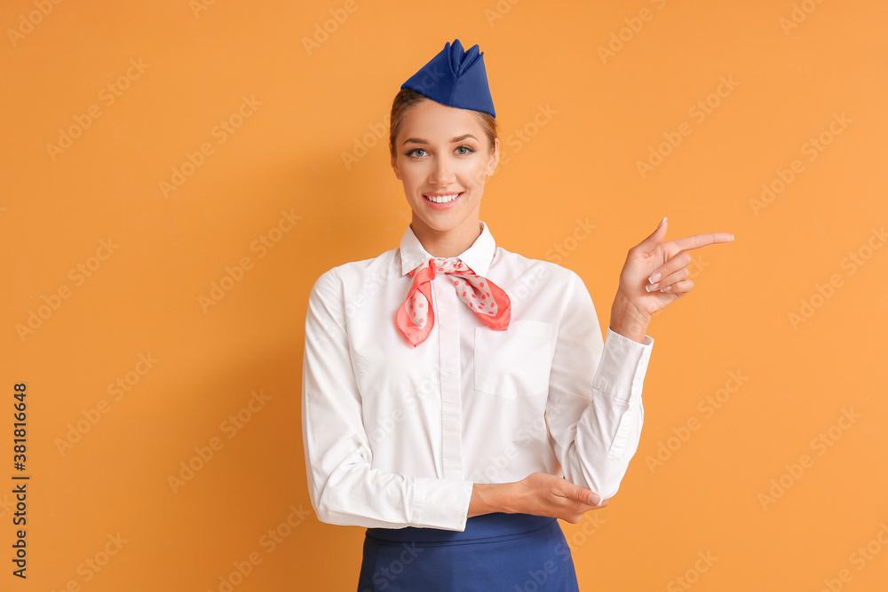 Beautiful stewardess pointing at something on color background