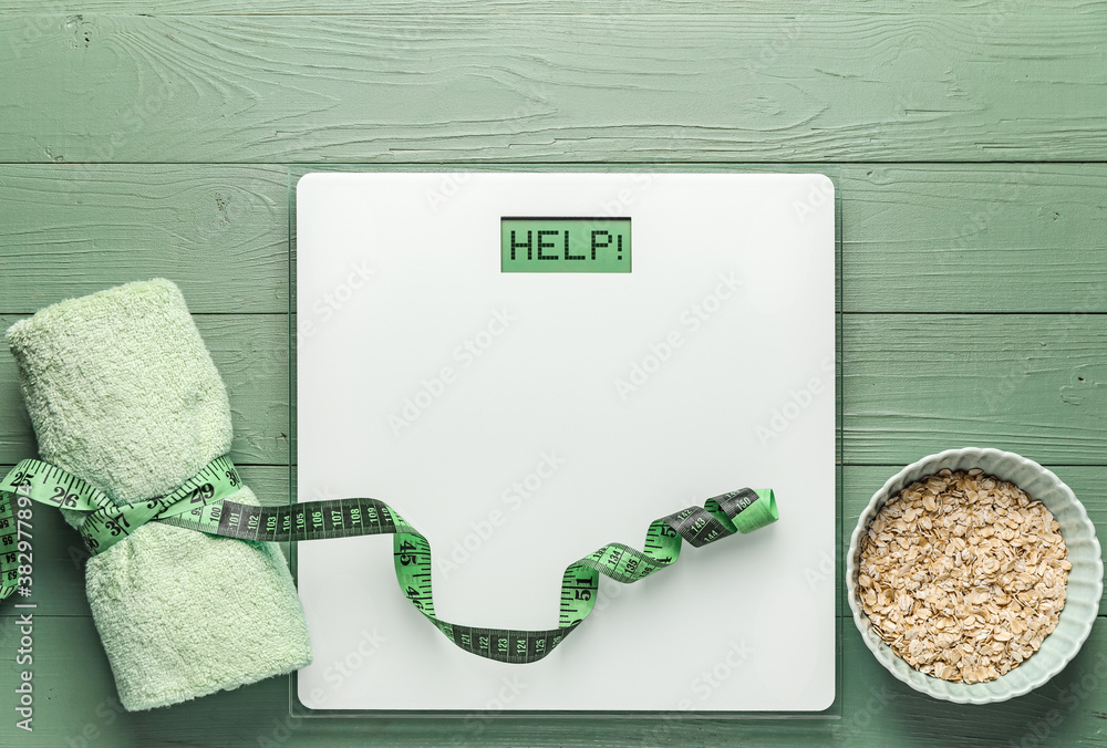 Scales with measuring tape, towel and oatmeal on wooden background. Weight loss concept