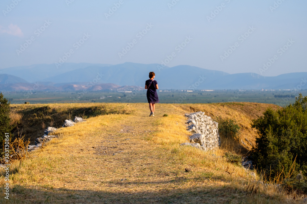 A single woman walking on a sun-lit path