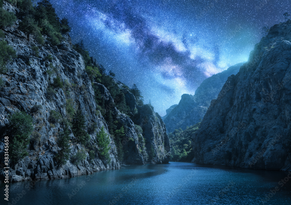 Milky Way over the beautiful mountain canyon and blue sea at night in summer. Colorful landscape wit