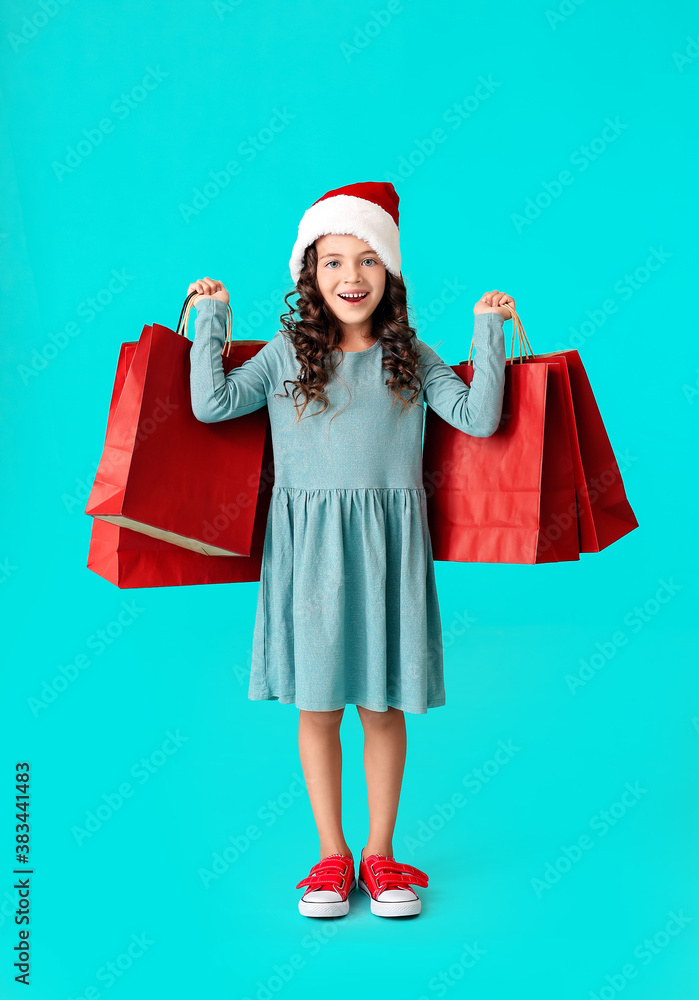 戴着圣诞老人帽，背景是购物袋的可爱小女孩