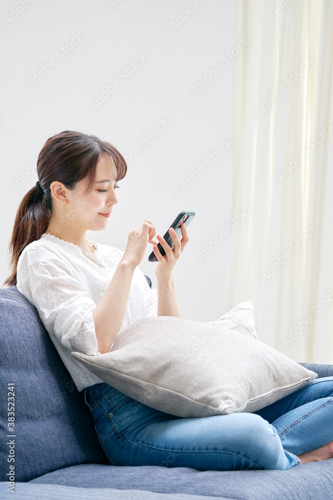ソファーでスマートフォンを使う女性